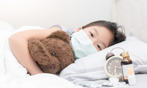 Sick girl with hygienic mask laying on bed, healthy concept
