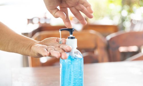 Close up Woman Pouring sanitising hand gel Into hand for outbreak prevention on restaurant background. Health care, Personal hygiene and Protection pandemic and concept.